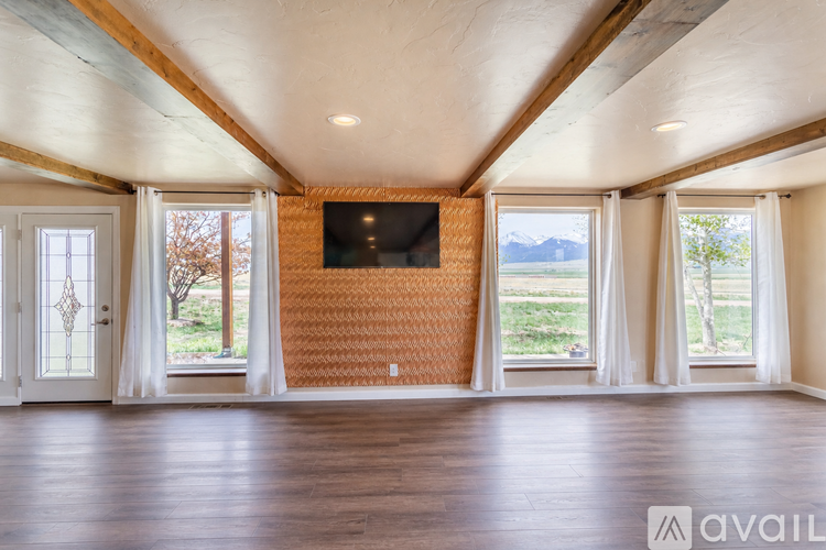 A spacious room with a television mounted on a brick wall and large windows.