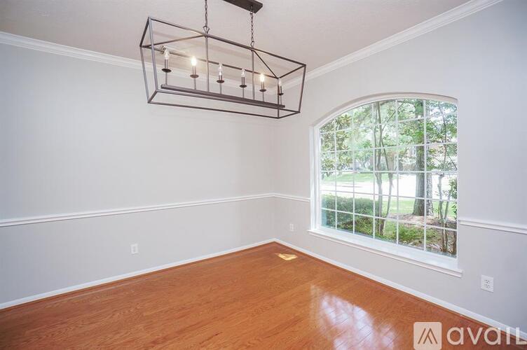 A room with wooden floors and a large window with a view of trees.