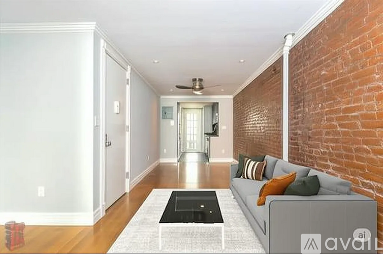 A living room with a grey couch and a brick wall.