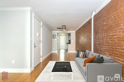 A living room with a grey couch and a brick wall.