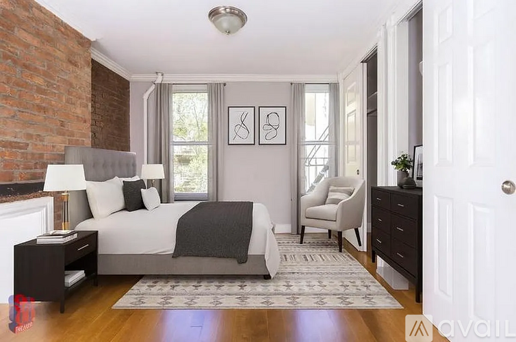 A bedroom with a brick wall and a white bed.