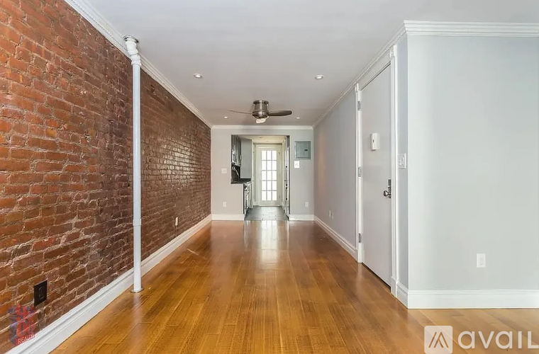 A long hallway with a brick wall on one side and a white door on the other.