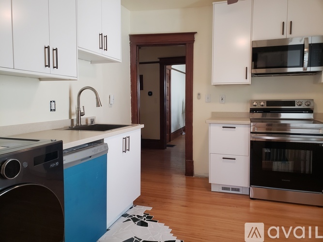 A kitchen with white cabinets and a blue dishwasher.