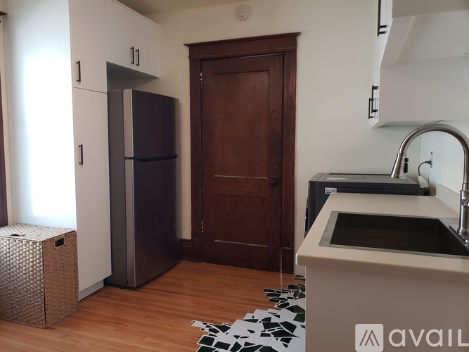 A kitchen with a sink, refrigerator, and a door.