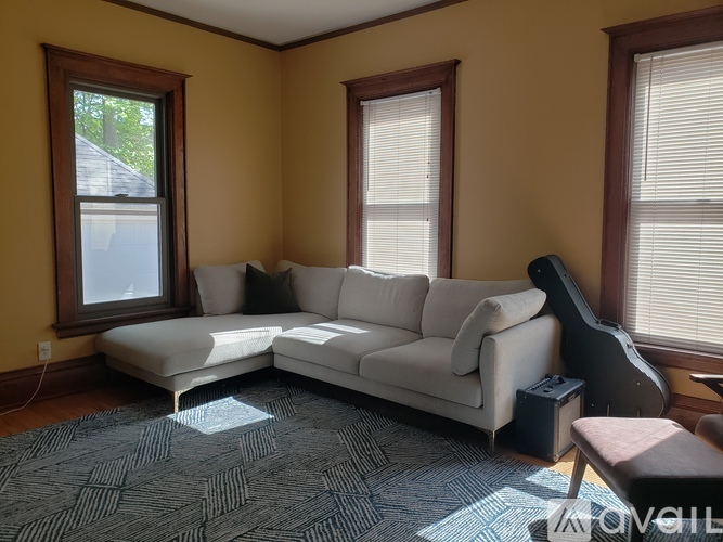 A living room with a white couch and a guitar.