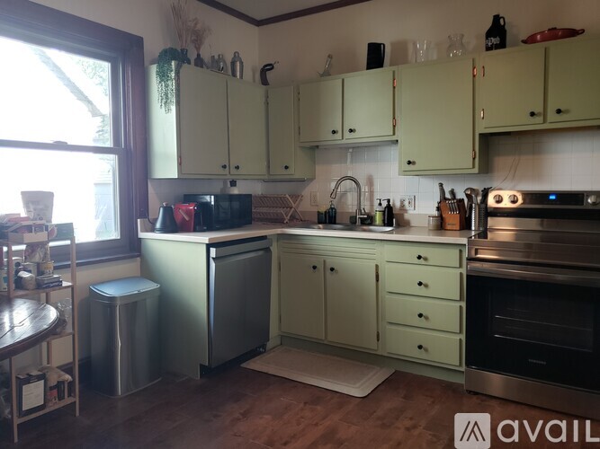 A kitchen with green cabinets and a stainless steel refrigerator.