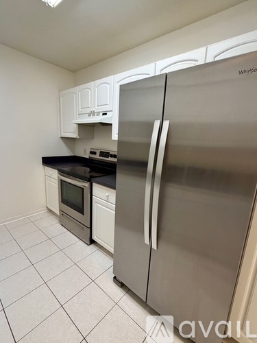 A kitchen with a stainless steel refrigerator and white cabinets.