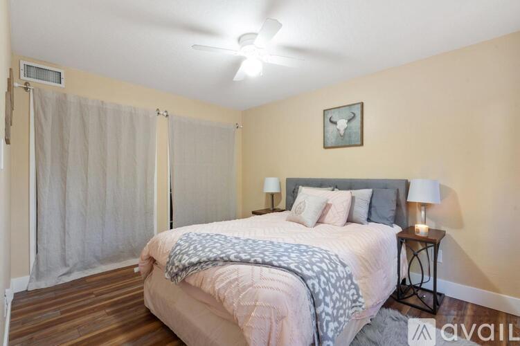 A bedroom with a bed, a ceiling fan, and a nightstand with a lamp.