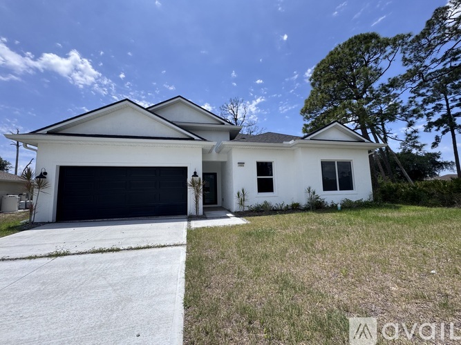 A white two-story house with a black garage door is for sale.