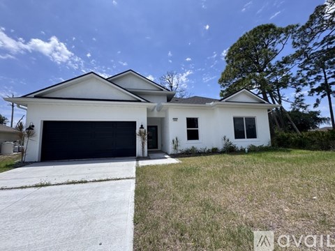 A white two-story house with a black garage door is for sale.