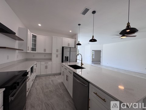 A modern kitchen with white cabinets and black countertops.