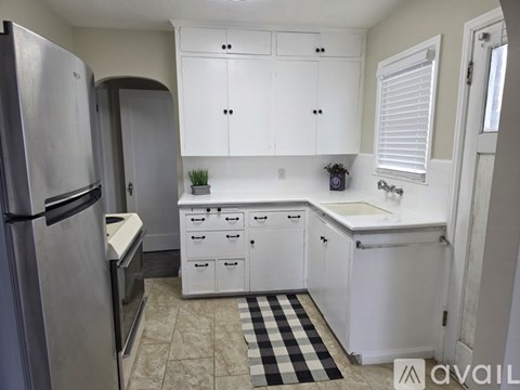 A kitchen with white cabinets and a black and white checkered rug.