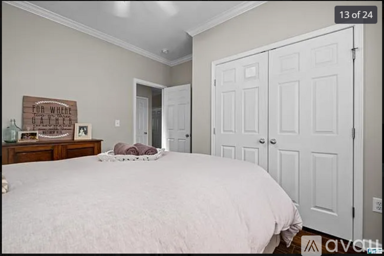 A bedroom with a large bed and a wooden sign on the wall.