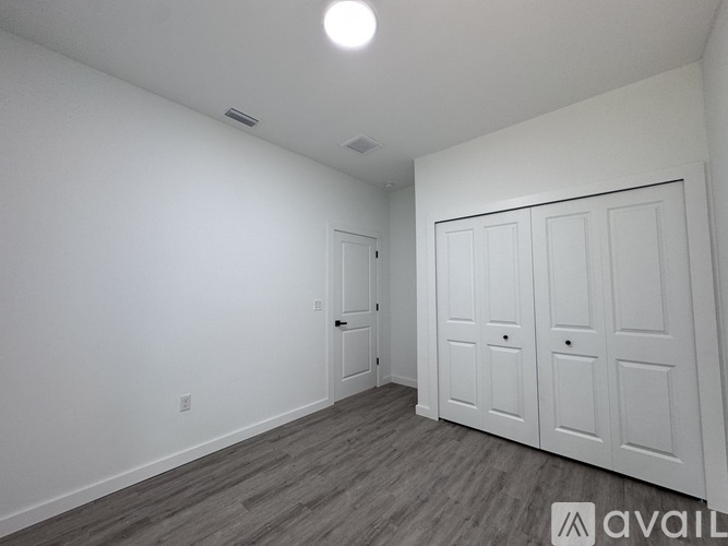 A room with a white door and a grey floor.