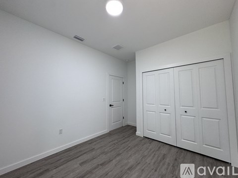 A room with a white door and a grey floor.