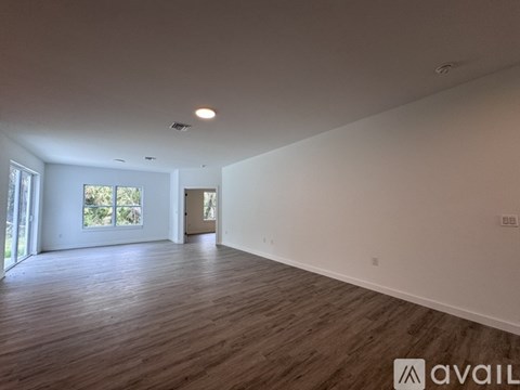 A spacious room with wooden flooring and white walls.