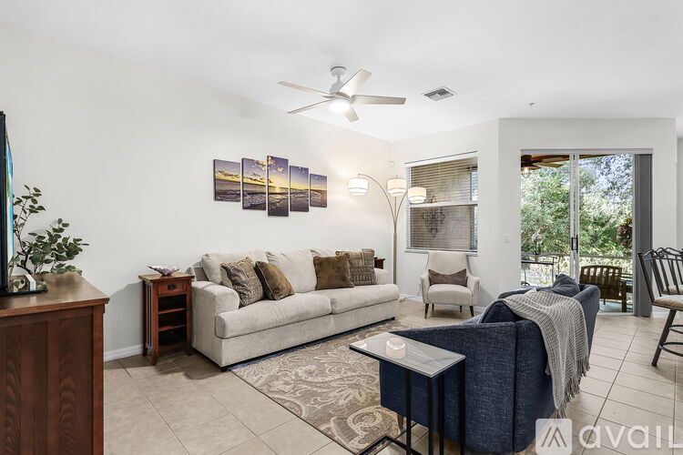 A living room with a couch, a chair, a coffee table, and a ceiling fan.