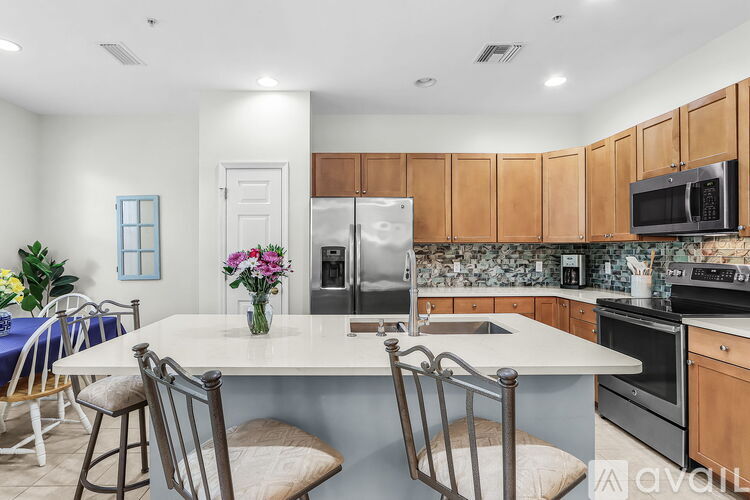 A kitchen with a table and chairs in the foreground and a refrigerator, microwave, and oven in the background.