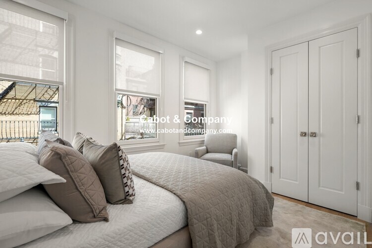 A bedroom with a large bed and a window overlooking a balcony.