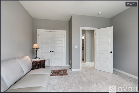 A living room with a white couch and a lamp on a side table.