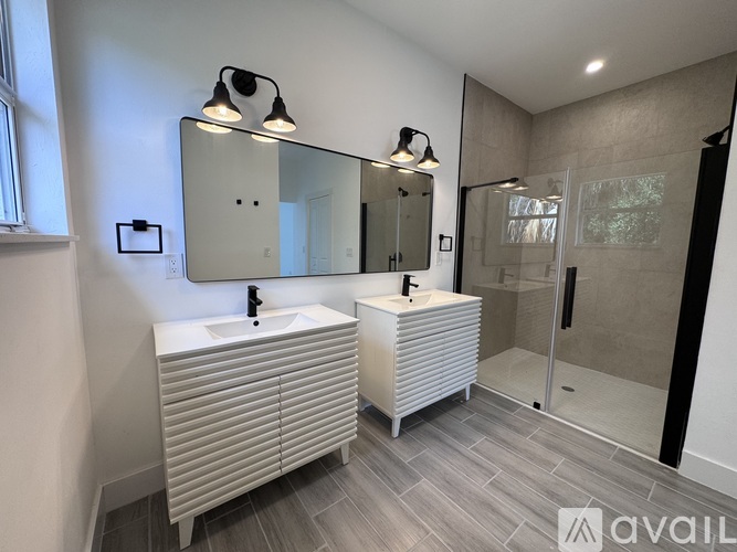 A bathroom with a sink, mirror, and a shower.