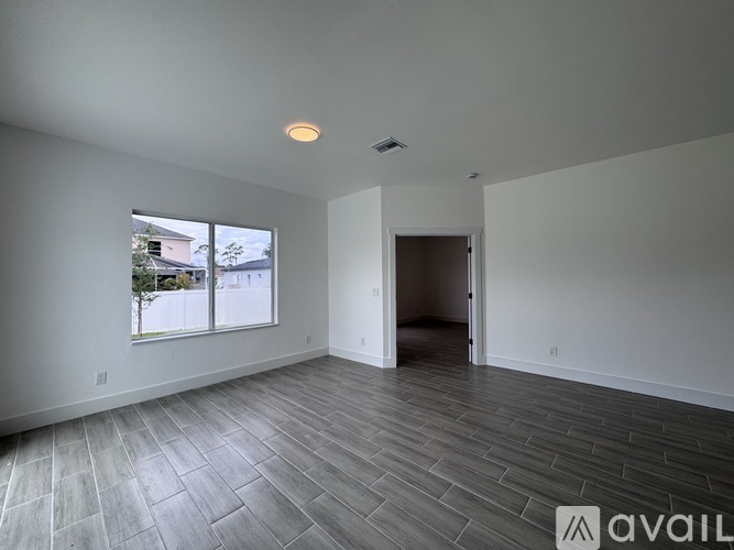 A spacious room with a large window and a door leading to another room.
