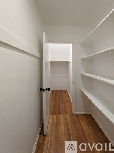A hallway with a black door and white walls.