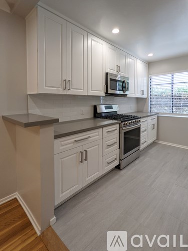 A kitchen with white cabinets and a stove top oven.