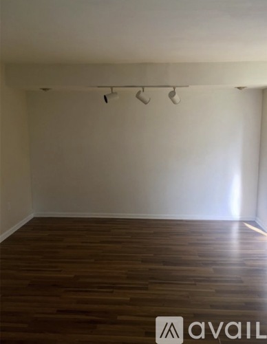 A room with wooden flooring and track lighting.