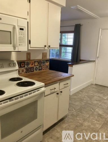 A kitchen with a white stove and cabinets.