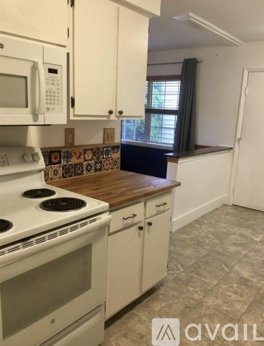 A kitchen with a white stove and cabinets.