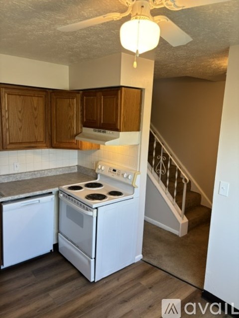 A kitchen with a white stove and wooden cabinets.
