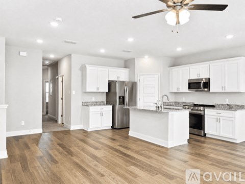 A spacious kitchen with white cabinets and a wooden floor.