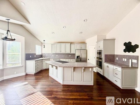 A modern kitchen with white cabinets and a wooden floor.