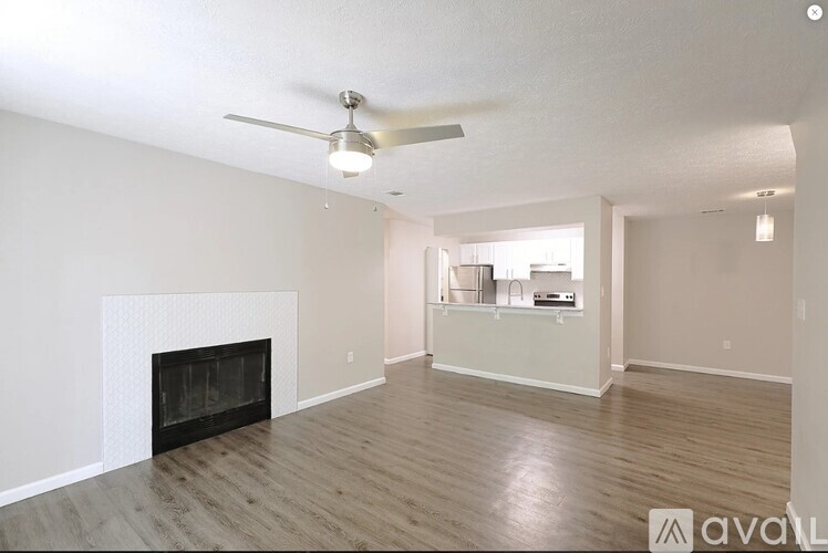 A spacious living room with a fireplace and a ceiling fan.