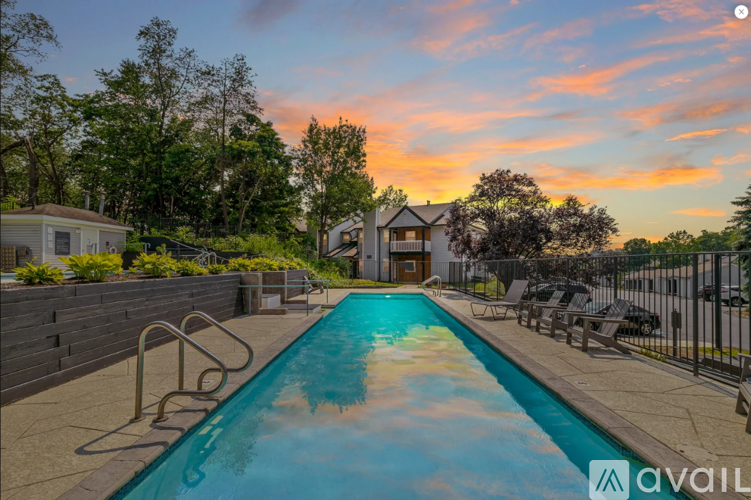 A pool surrounded by a fence and trees with a sunset in the background.