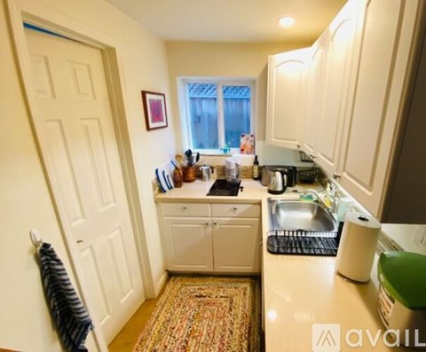 A kitchen with white cabinets and a rug on the floor.