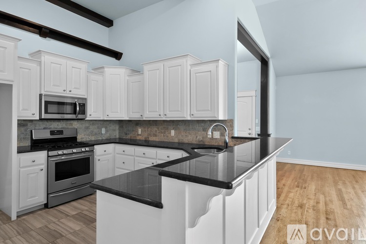 A kitchen with white cabinets and black countertops.