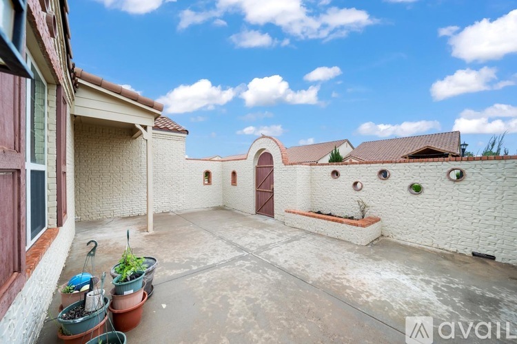 A courtyard with a white wall and a brown door.