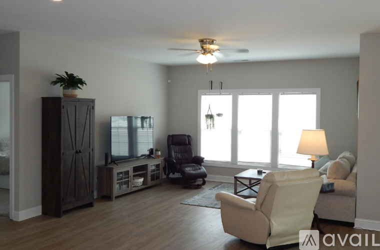 A living room with a beige chair, a brown cabinet, and a ceiling fan.