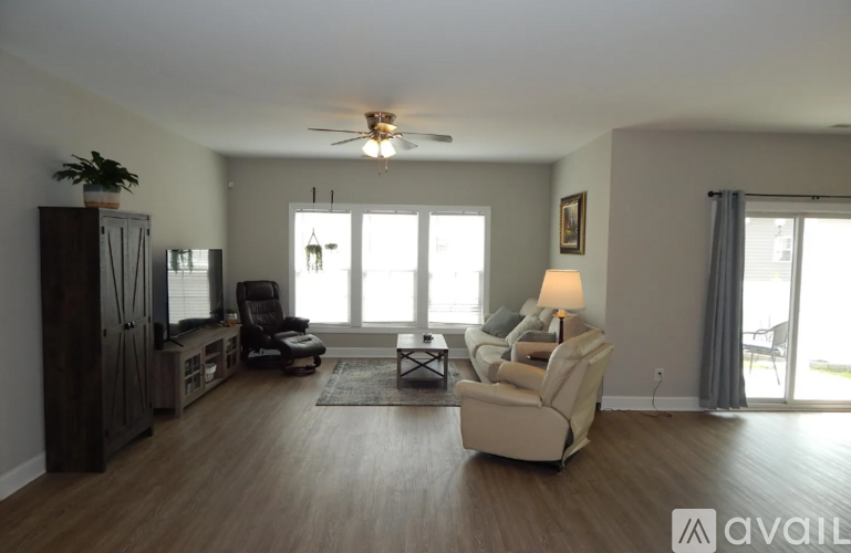 A living room with a ceiling fan and a large window.