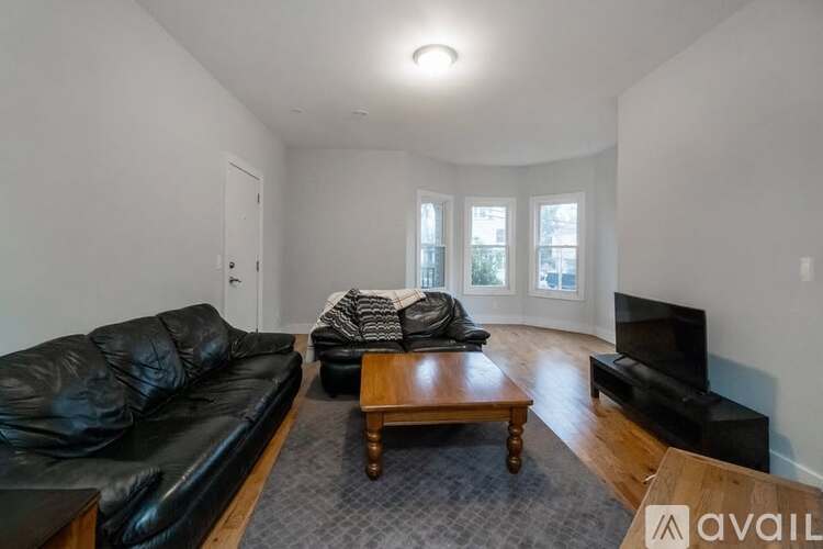 A living room with a black leather couch and a wooden coffee table.