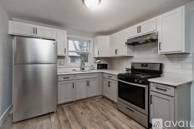 A kitchen with a stainless steel refrigerator, oven, and wooden floors.