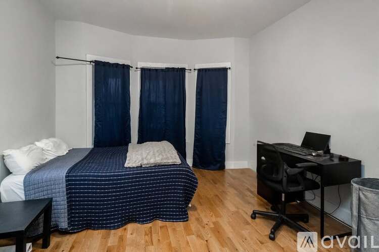 A bedroom with a bed, desk, and chair.