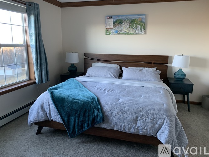 A bedroom with a large bed and a painting on the wall.