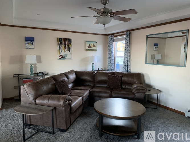 A living room with a brown leather couch and a round table.