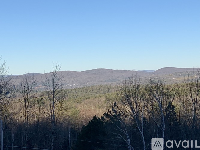 A landscape with trees and hills under a clear sky.