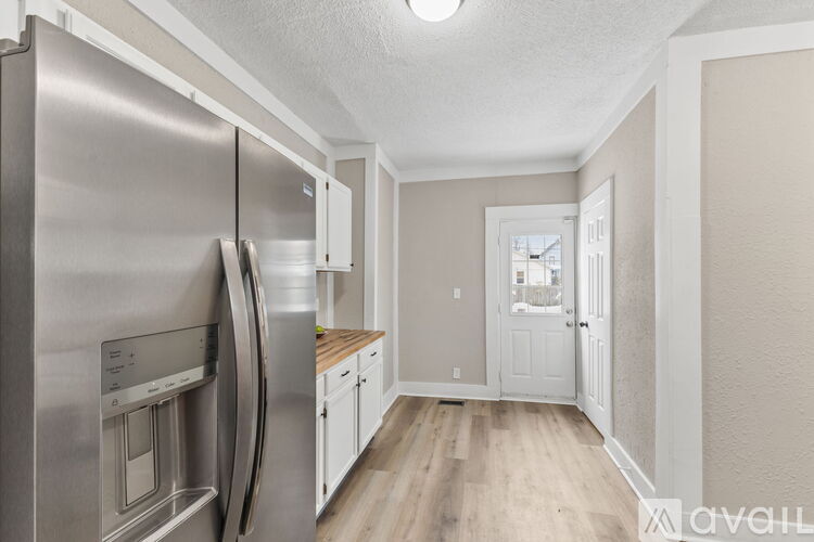 A modern kitchen with a stainless steel refrigerator and wooden flooring.