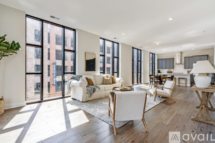 A spacious living room with white furniture and large windows.