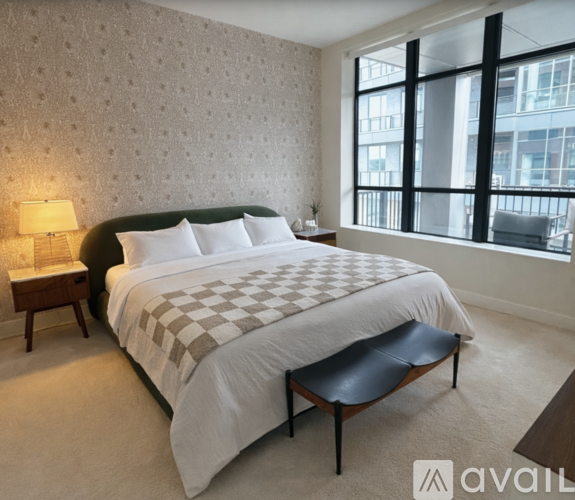 A bedroom with a large bed and a window overlooking a cityscape.